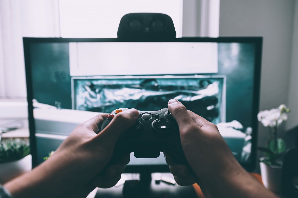 person holding game controller in-front of television