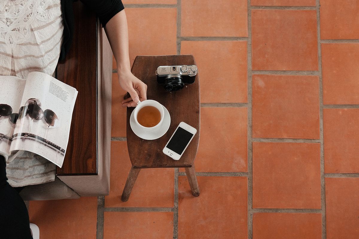 person sitting on sofa while reading brochure holding teacup