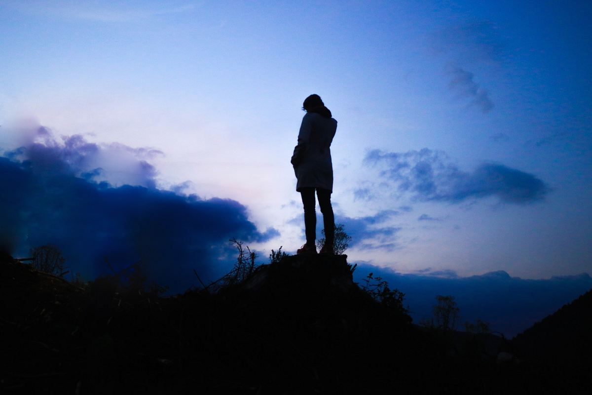 person standing on boulder during twilight