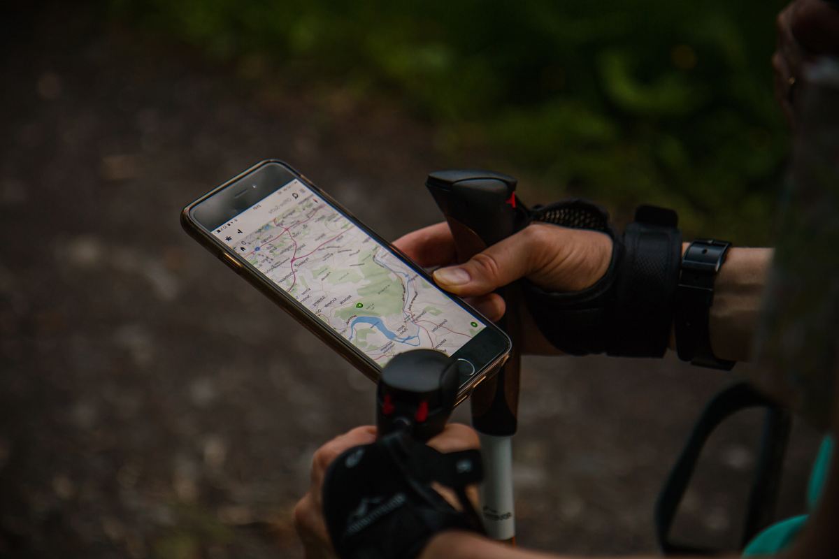 person using smartphone with nordic walking sticks