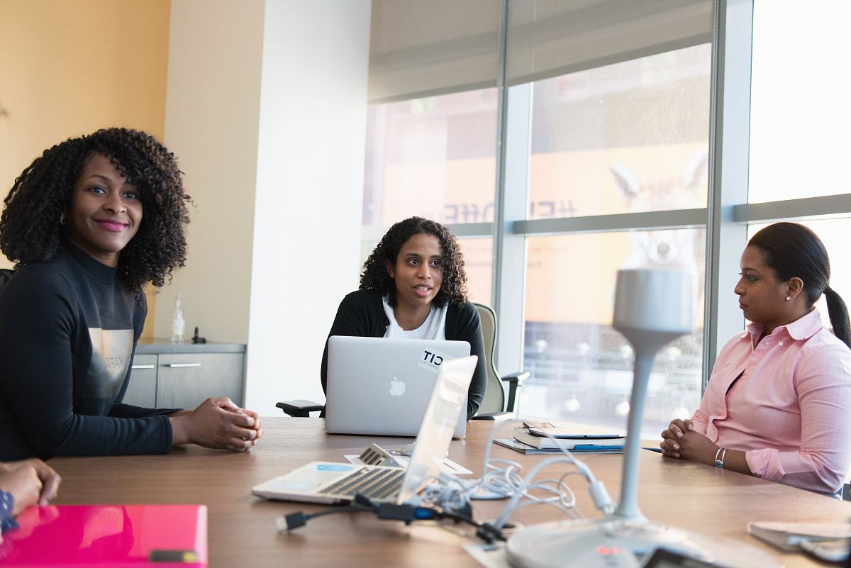 photography of three women sits beside table inside room during daytime