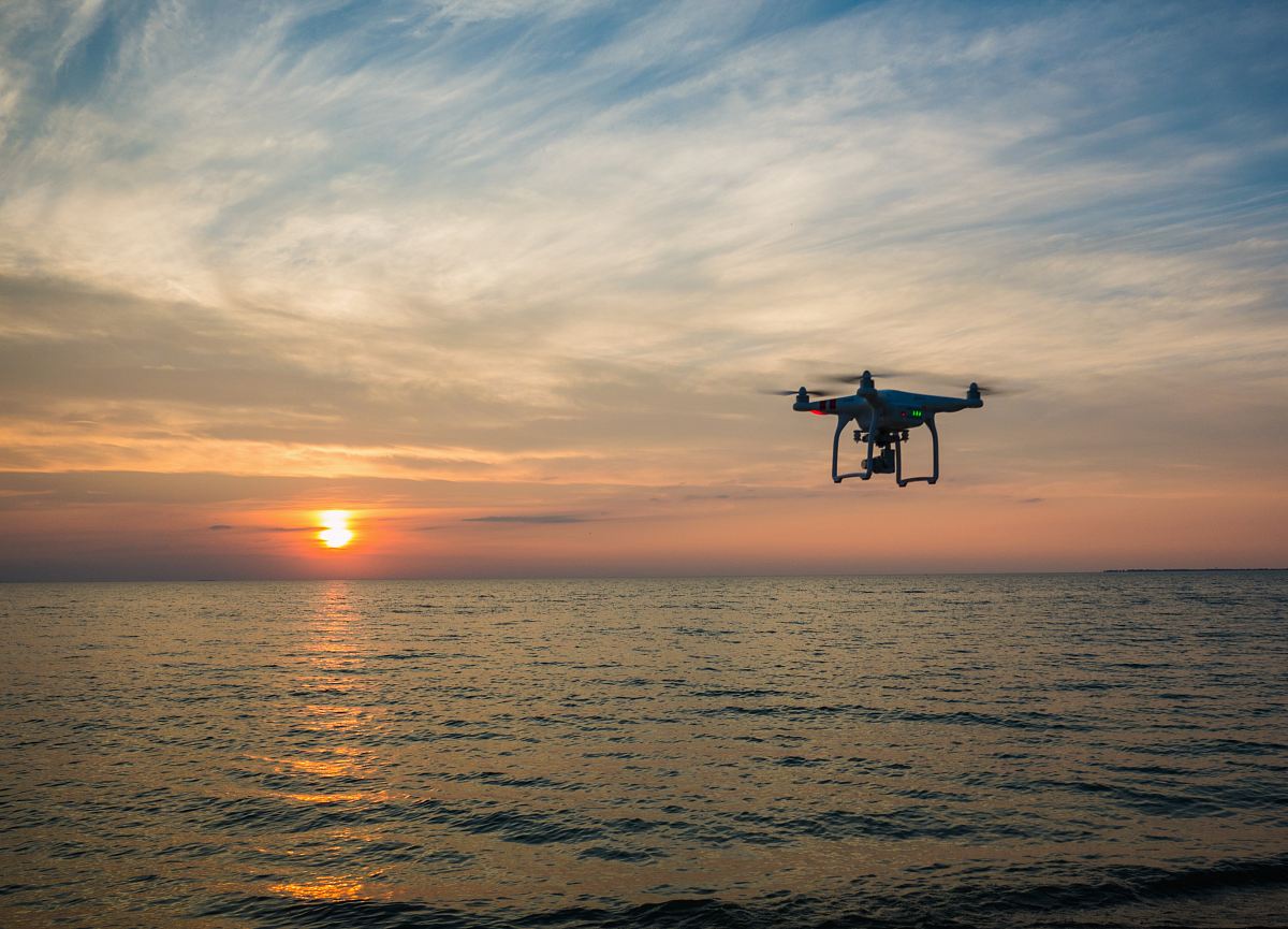 quadcopter flying over body of water