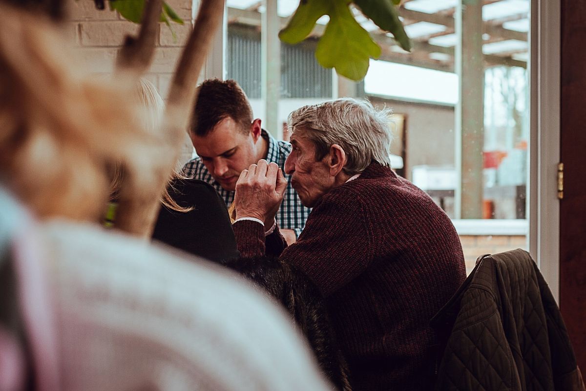 shallow focus photography of man sitting in front of the table while holding his hands together