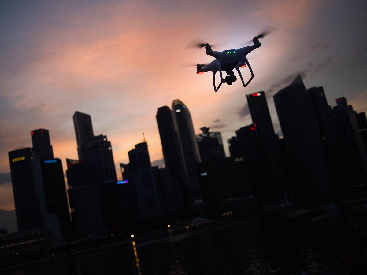 silhouette of quadcopter drone hovering near the city