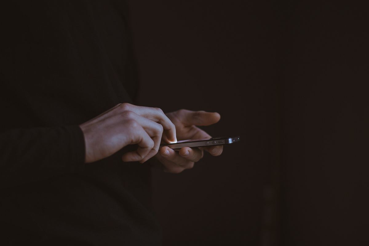 silhouette photo of person holding smartphone