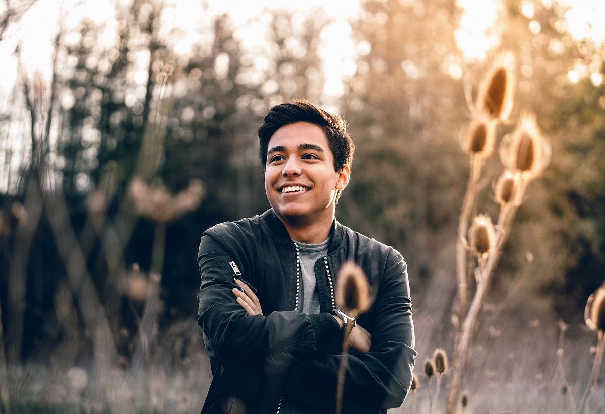 smiling man standing near green trees