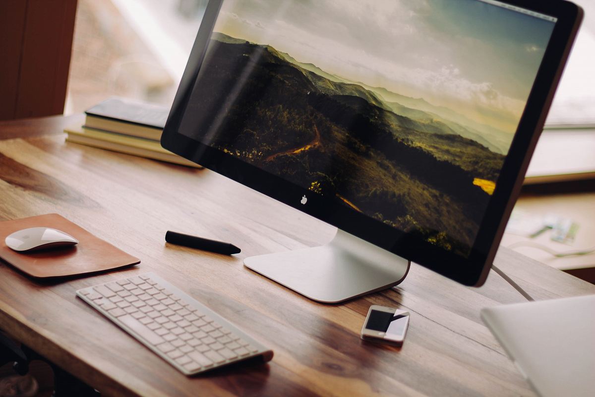 space gray iMac near Magic Keyboard on brown wooden computer desk during daytime