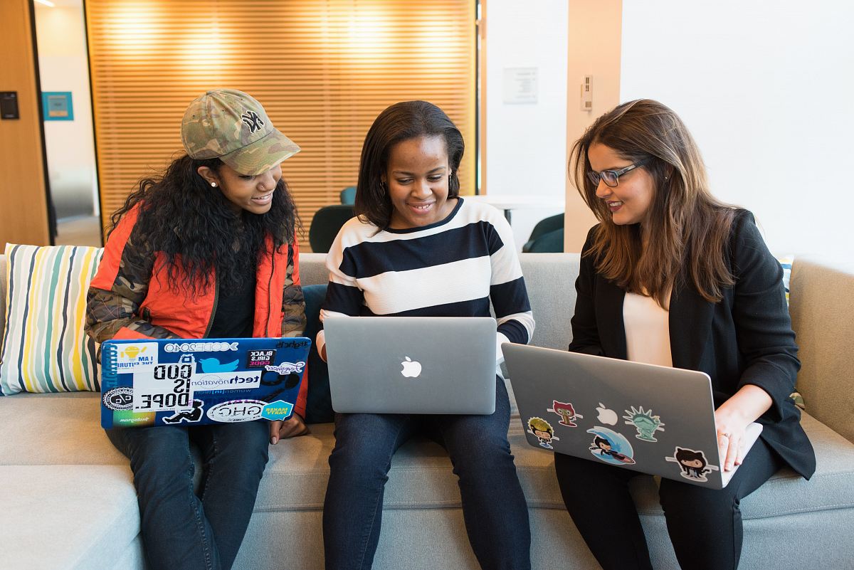 three women sitting on sofa with MacBook