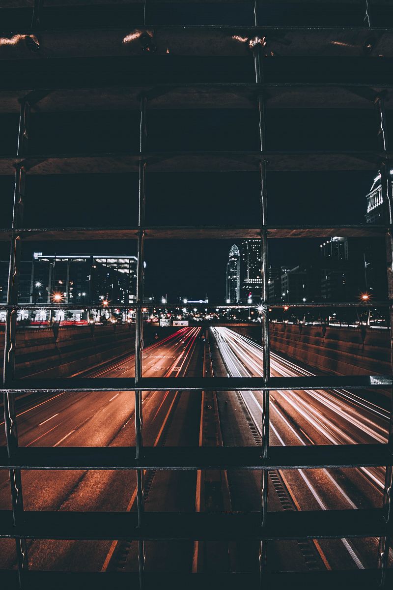 time-lapse photo of road with light streaks view behind grills