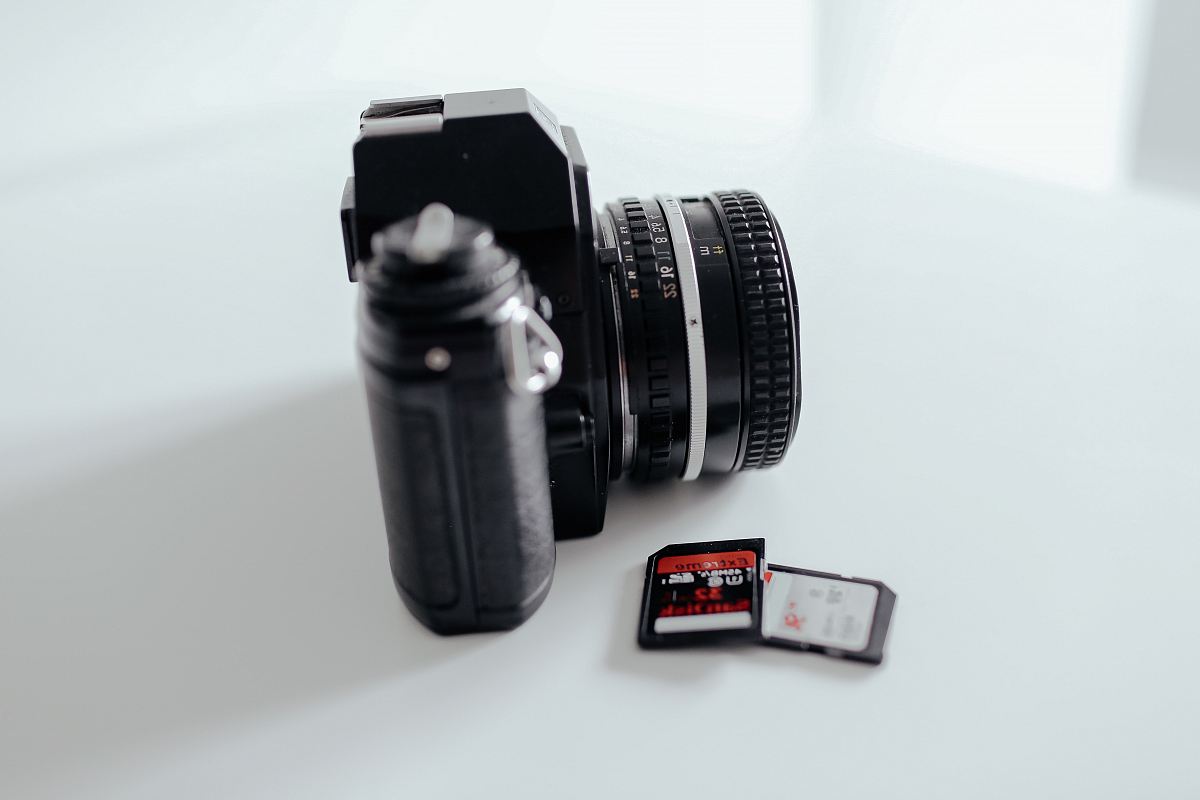 two black memory cards beside black DSLR camera on white surface