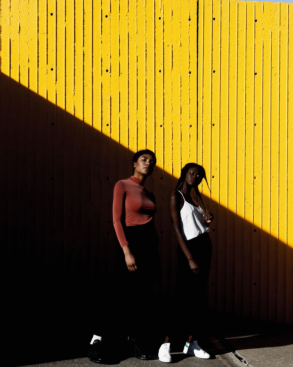 two women standing in front of yellow wall