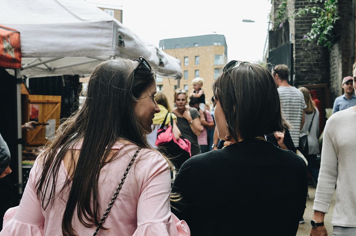 two women walking near food stalls