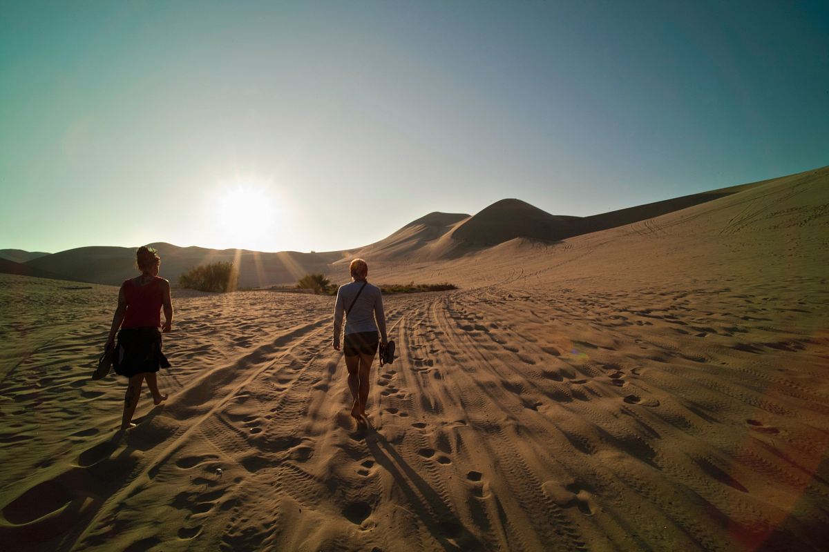 two women walking on sand during daytime