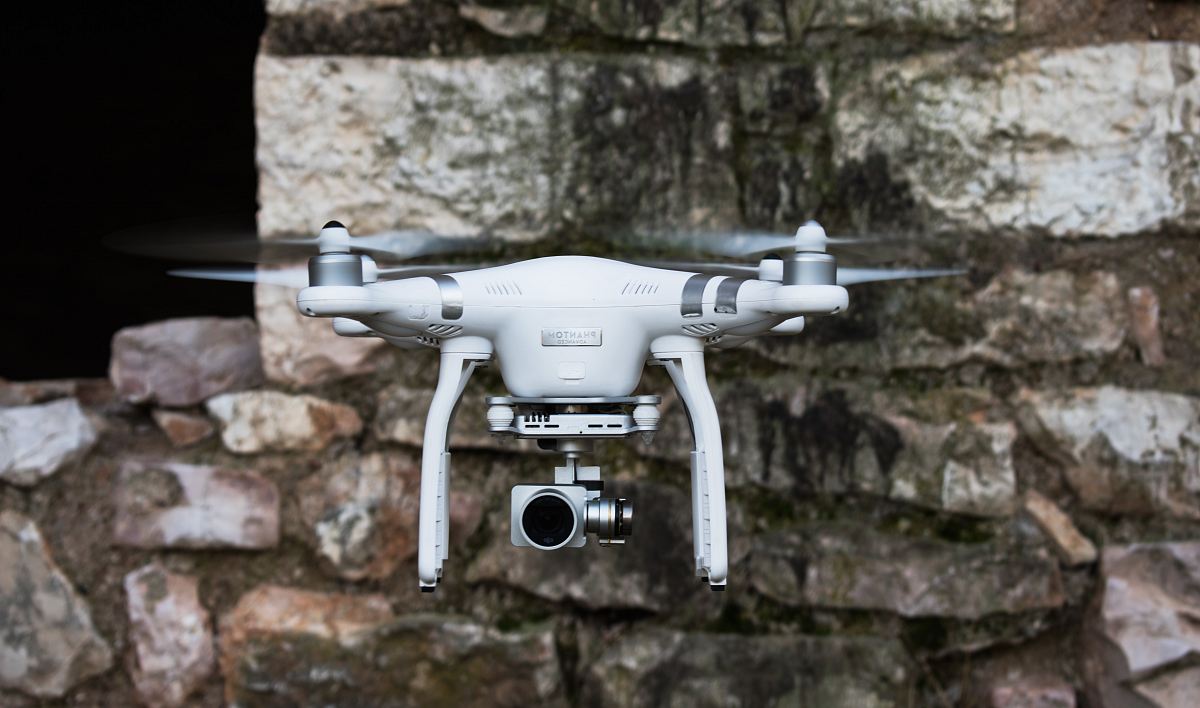 white and silver DJI quadcopter near brown concrete wall during daytime