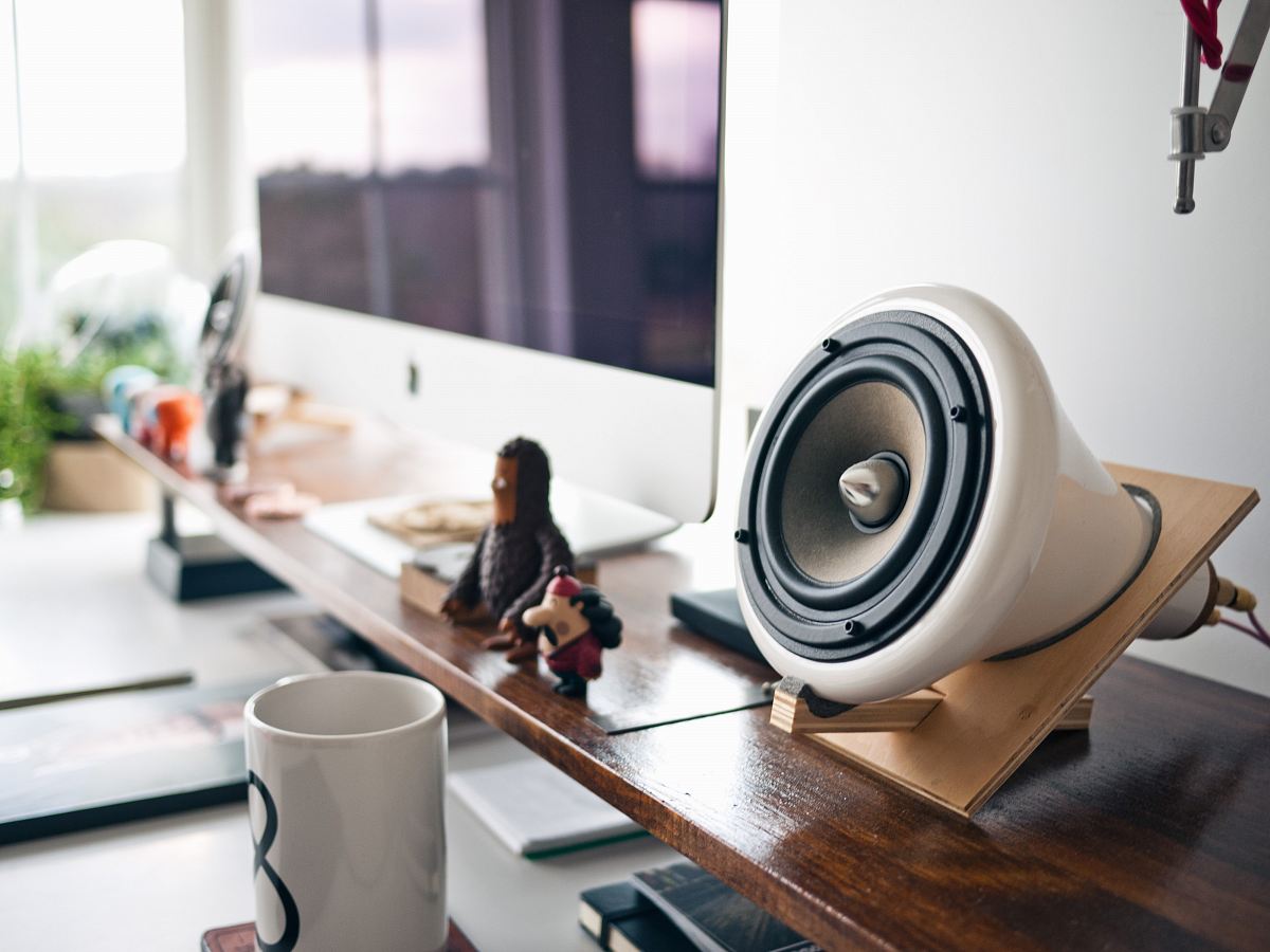 white speaker in brown holder beside silver Imac