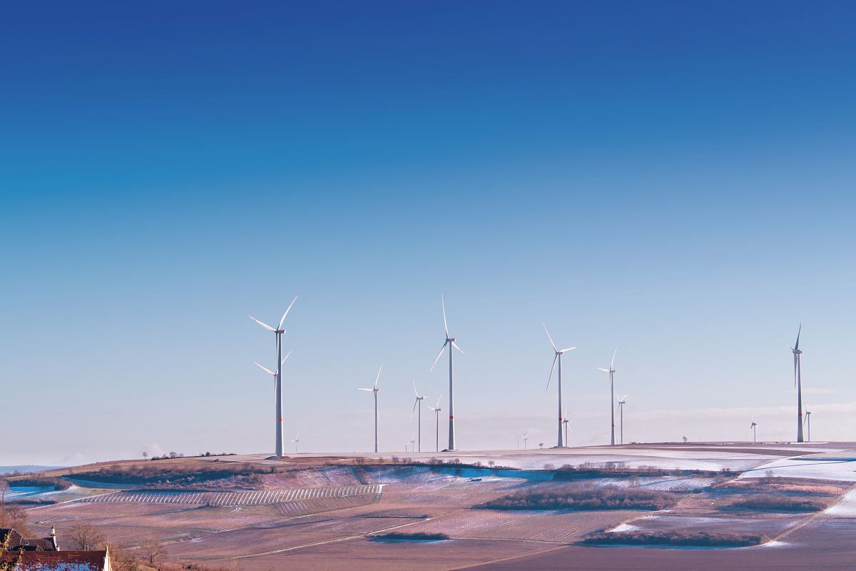 white wind turbine on grey desert under blue and white sky