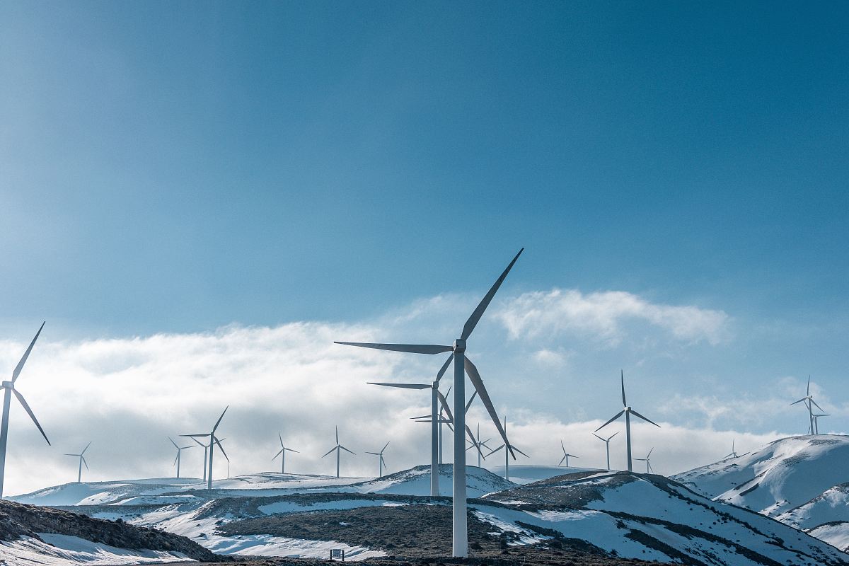 wind turbines on snowy mountain under clear blue sky during daytime