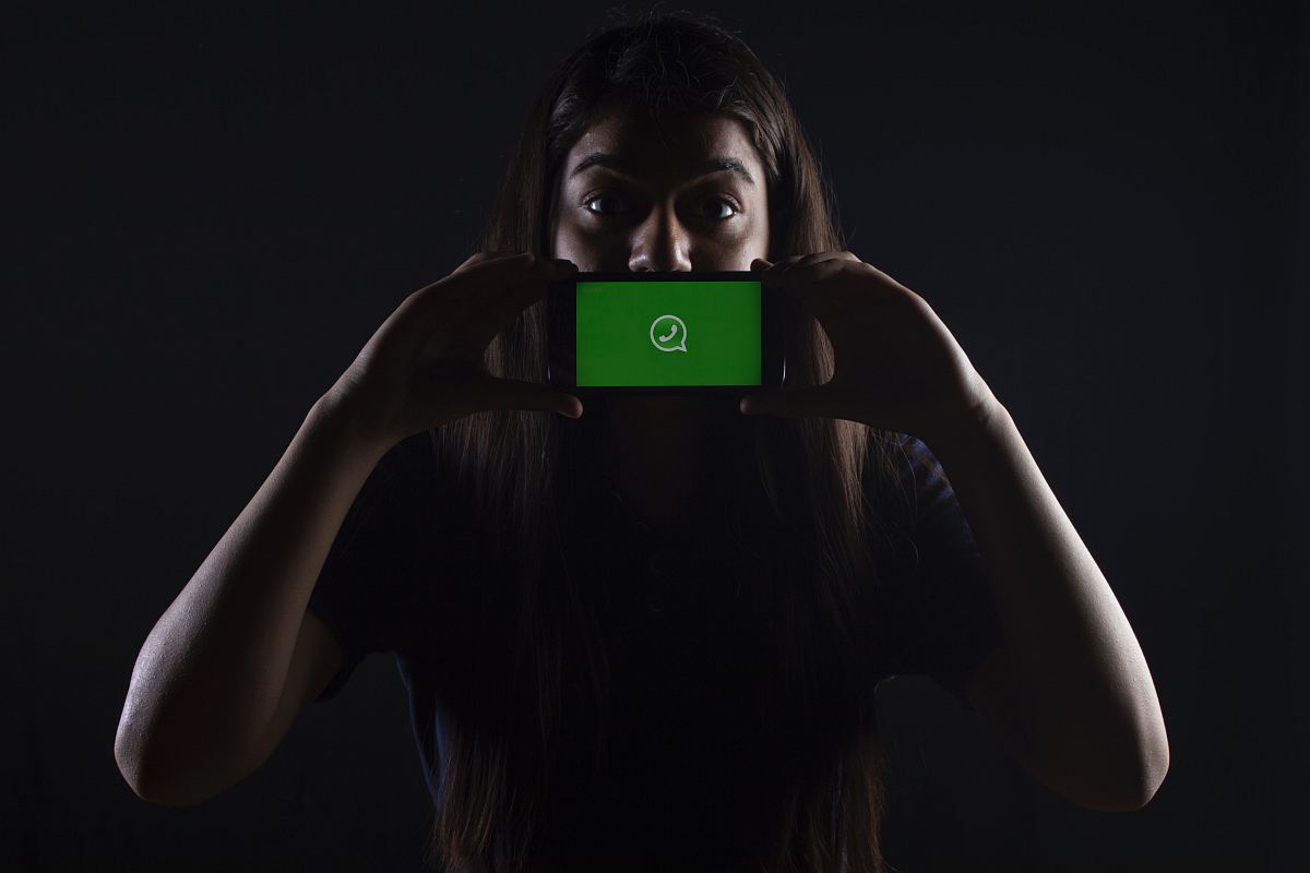 woman holding black smartphone at Whatsapp logo