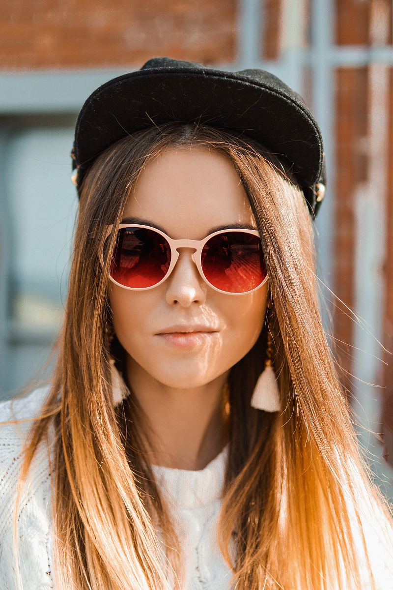woman in white knit sweater and black fitted cap