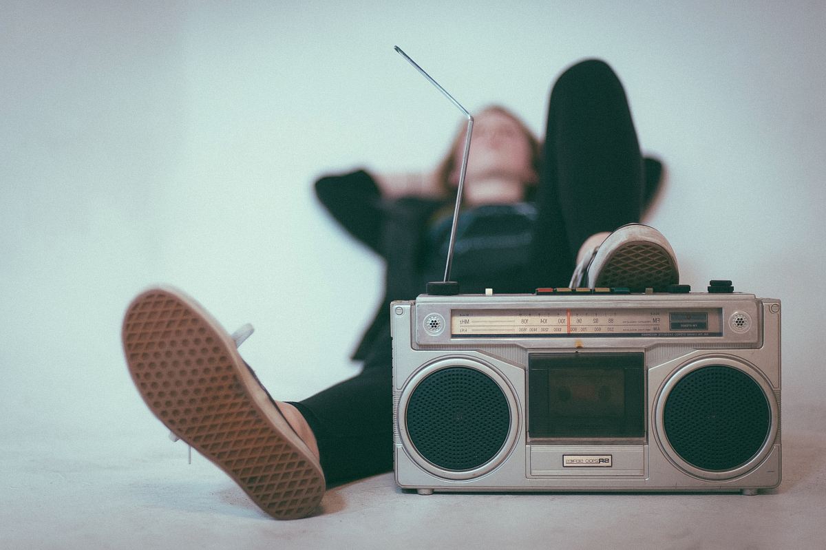 woman laying on bed near gray radio