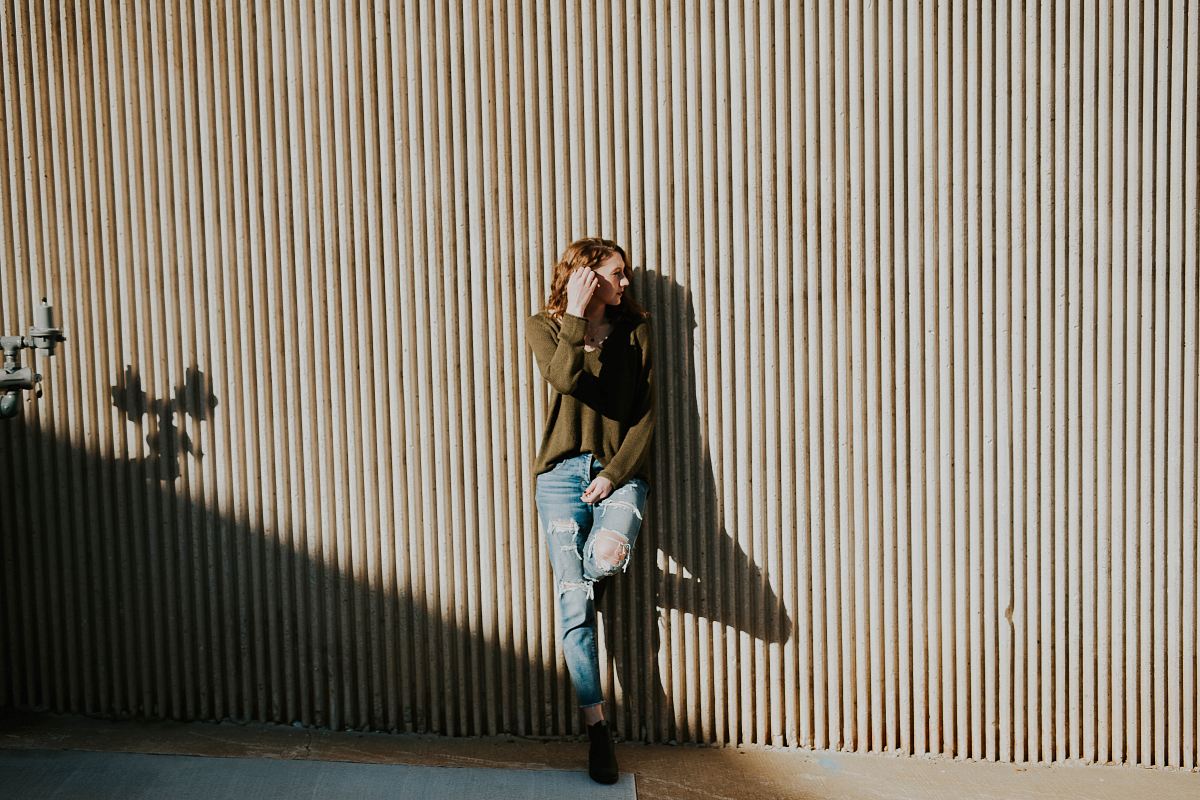 woman leaning on beige wall with shadow at daytime