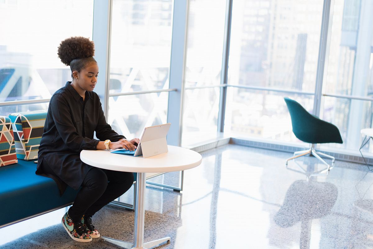 woman sits of sofa while using tablet computer