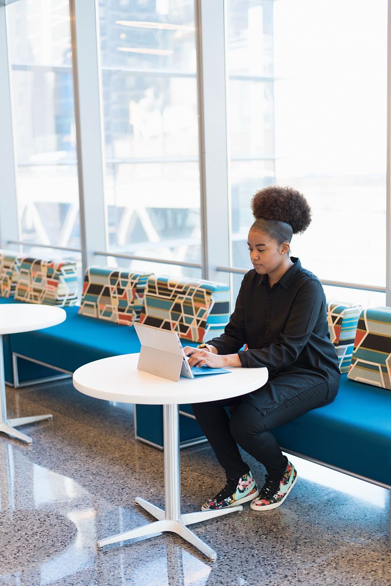 woman sits on sofa while using laptop computer