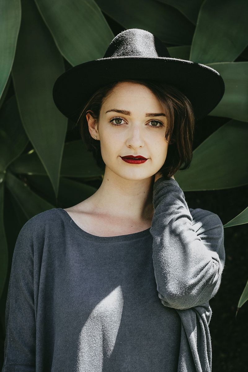 woman standing near trees wearing black hat