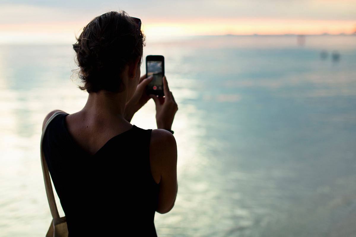 woman taking photo of body of water