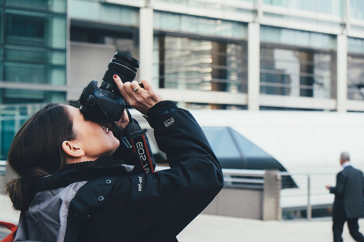 woman wearing gray and black jacket using DSLR camera