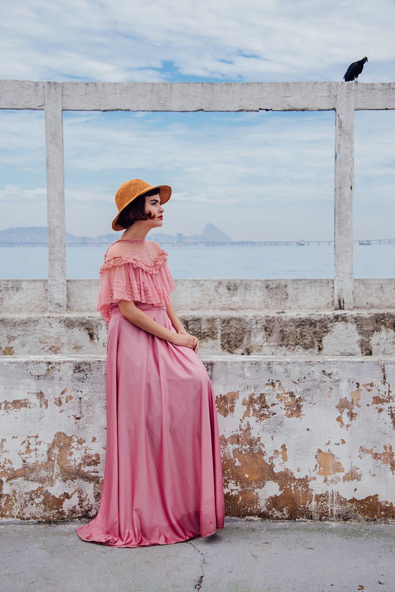 woman wearing pink dress standing next to white wall