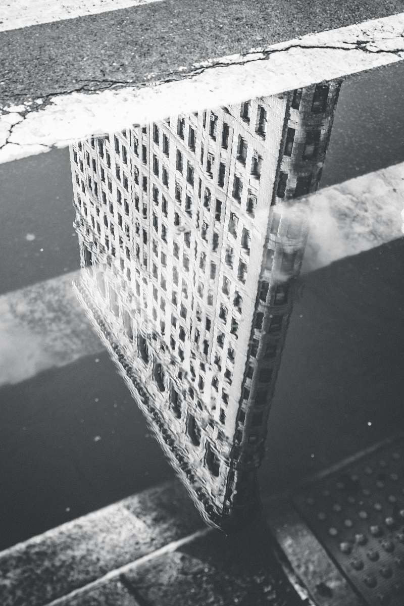  grayscale photography of reflection of building on body of water 