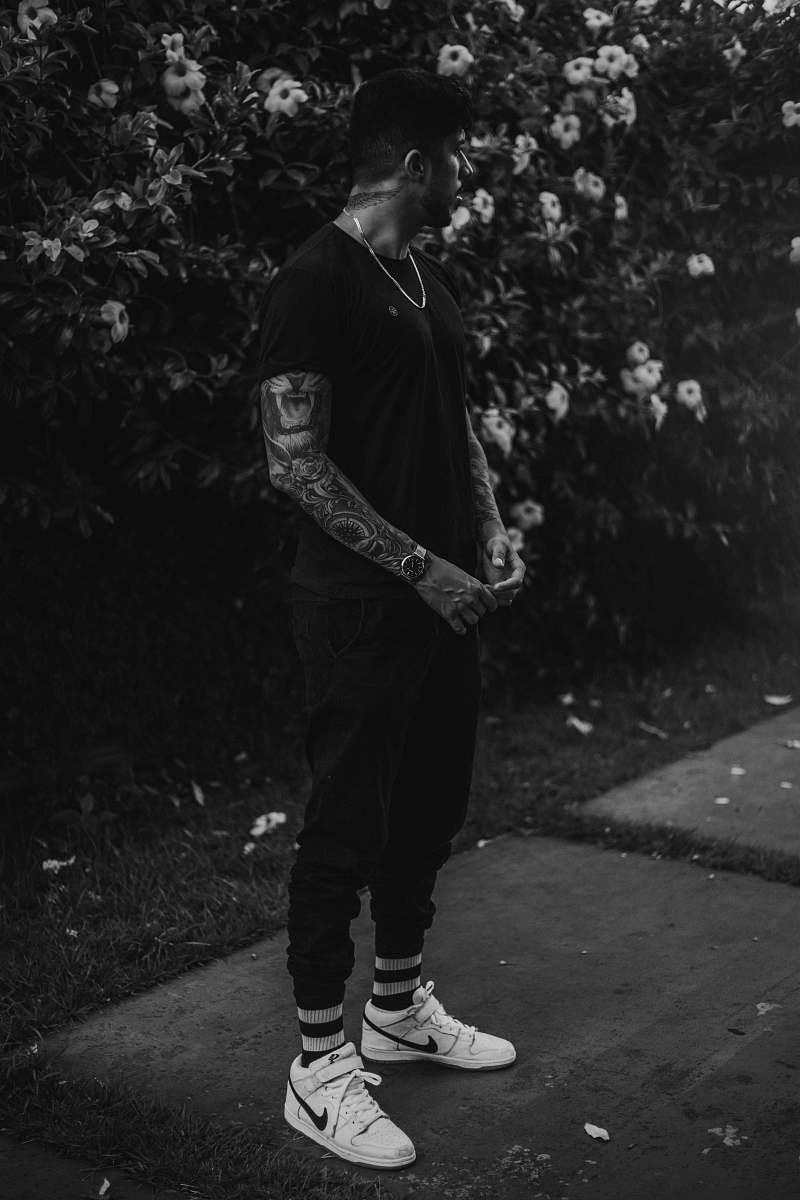 apparel man with tattoo on his arms standing near bushes clothing