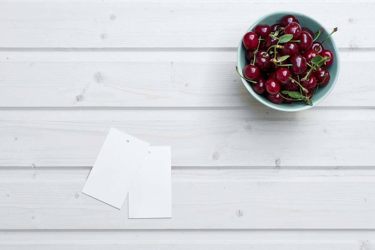 fruit cherries in bowl beside paper cherry