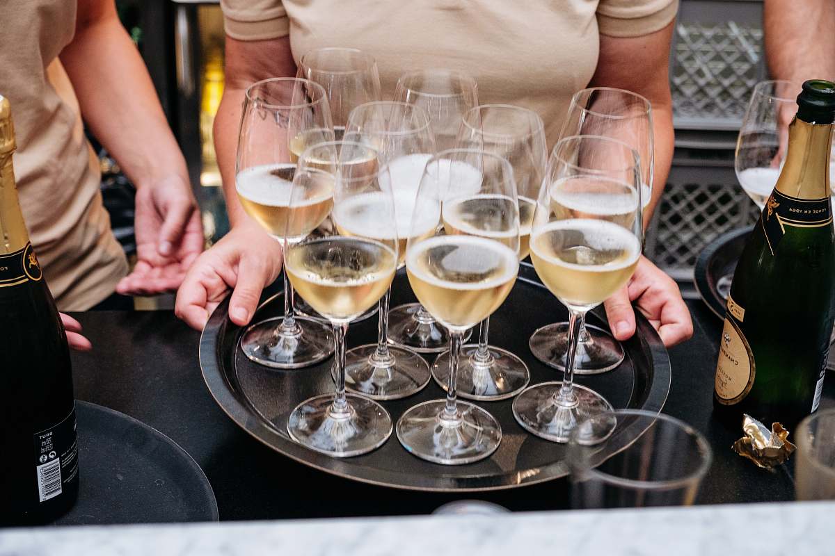 person person holding tray with drinking glasses glass