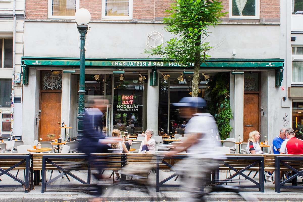 restaurant timelapse photo of person riding bike passing by storefront during daytime cafe