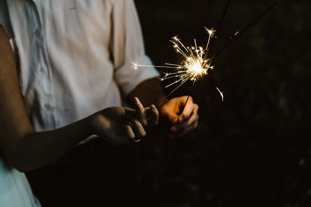 fire two person holding sparklers hand