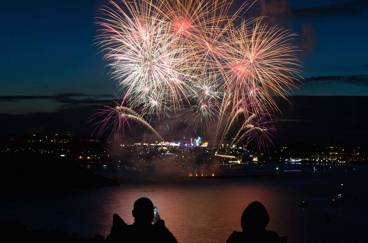 night silhouette of two person taking photo of fireworks fireworks
