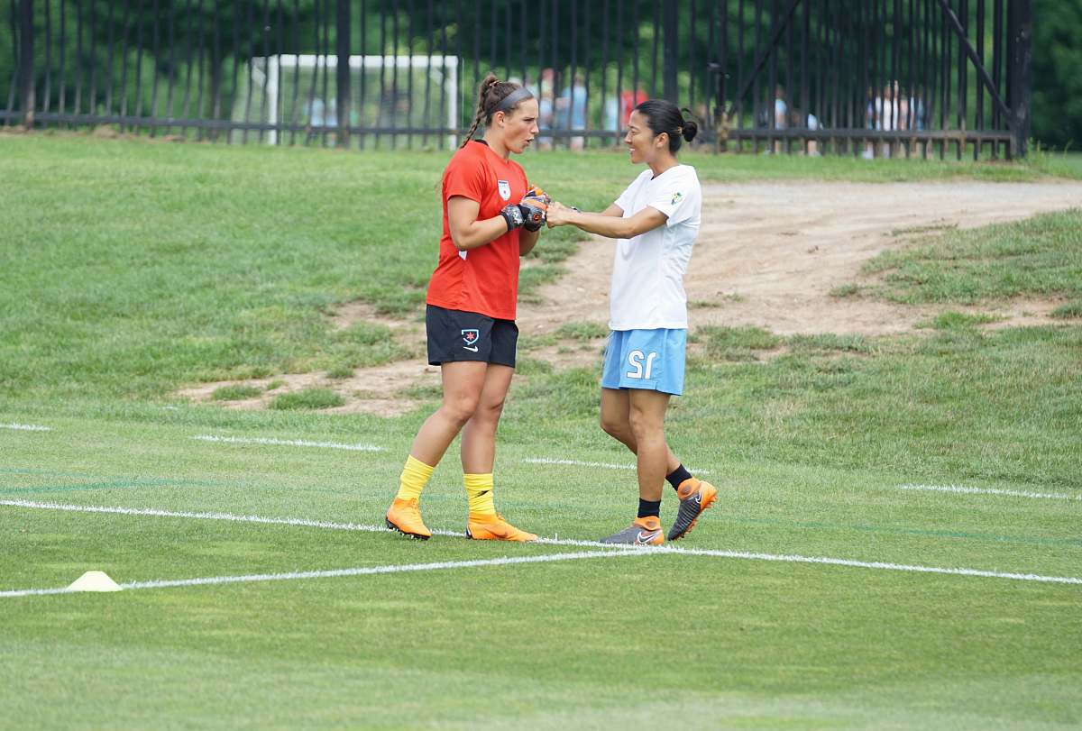 human two women fist bumping on field sport