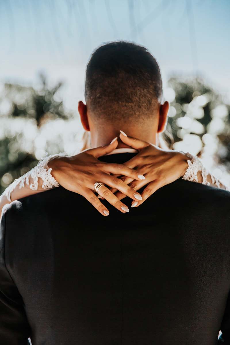 human bride with hands on back of man wearing black formal top wedding