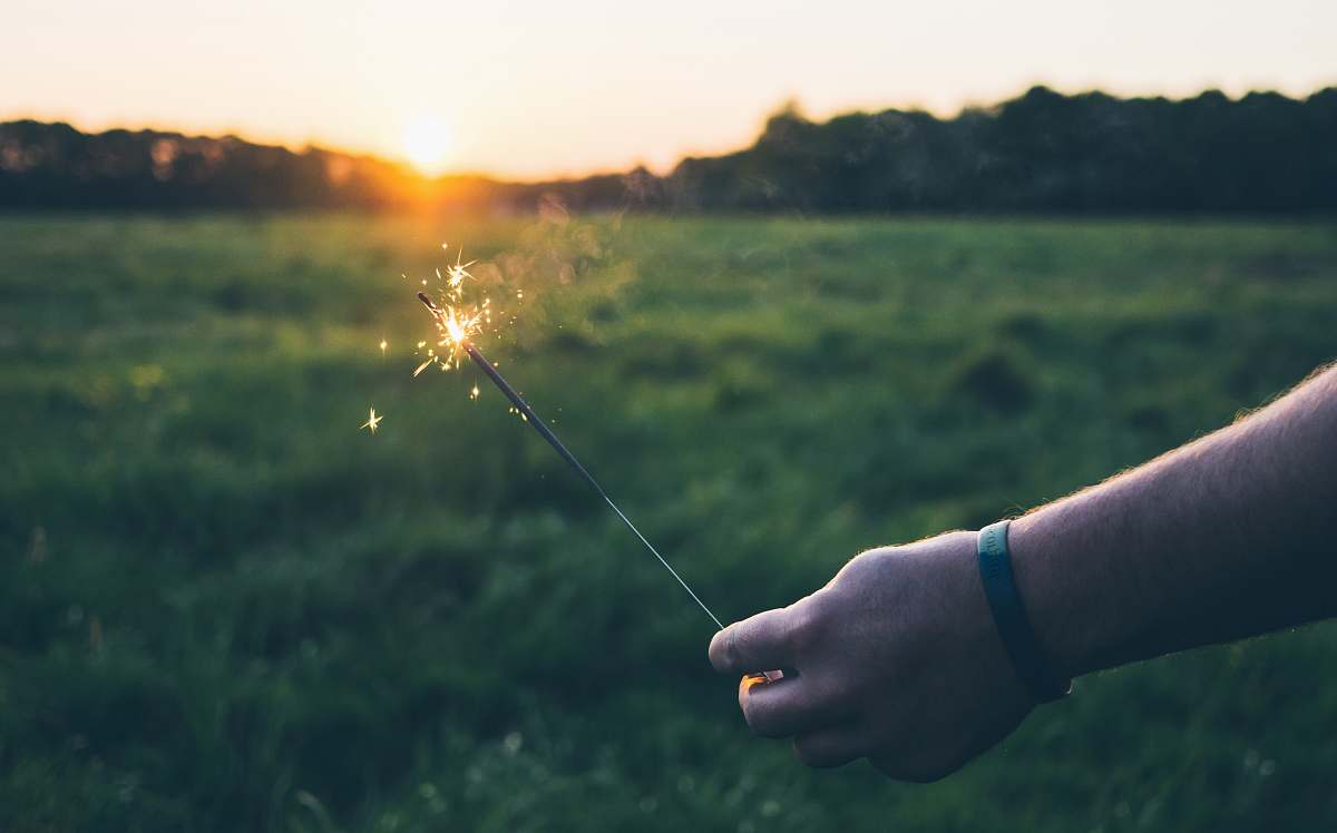 spark person holding fire stick sunset