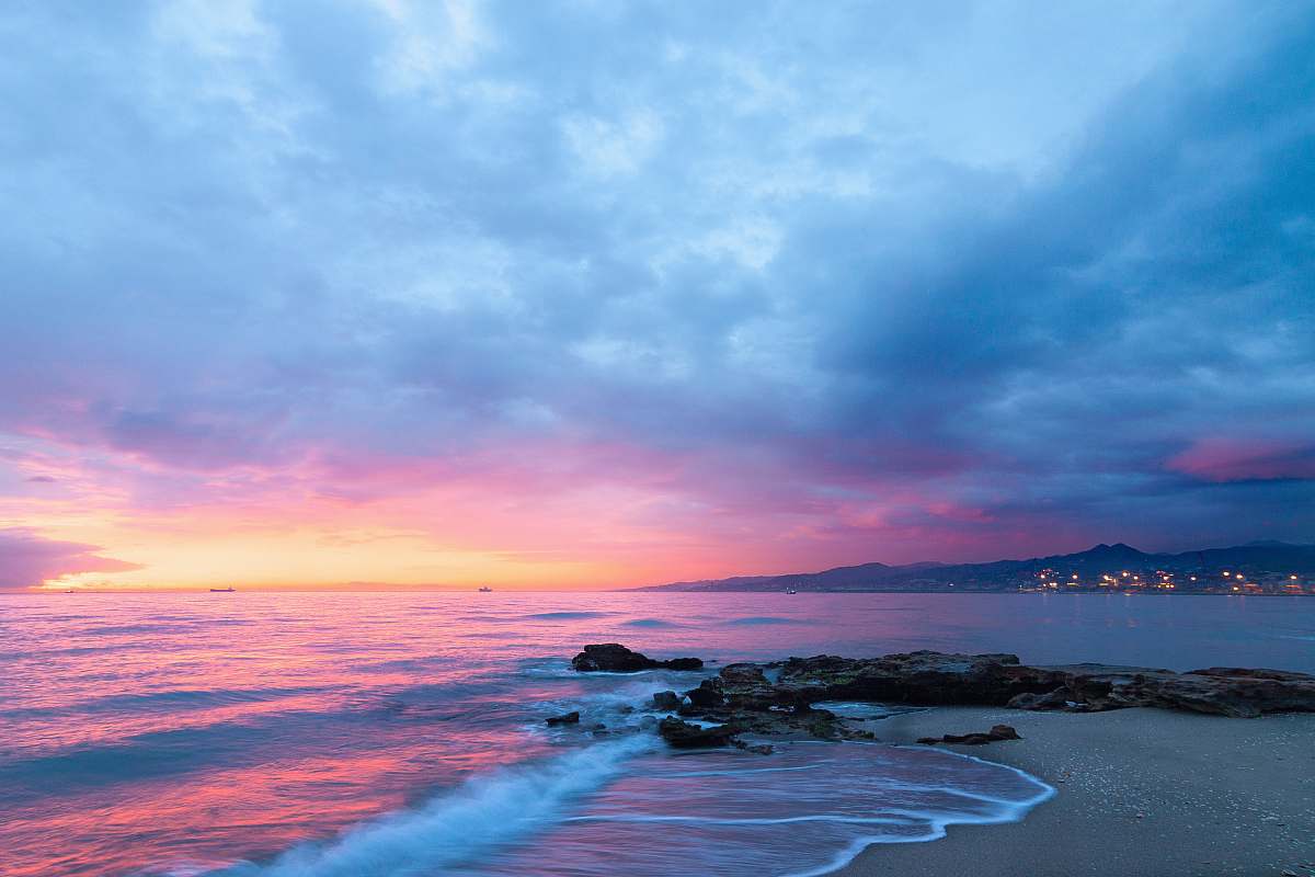 sky waves of body of water splashing on sand beach