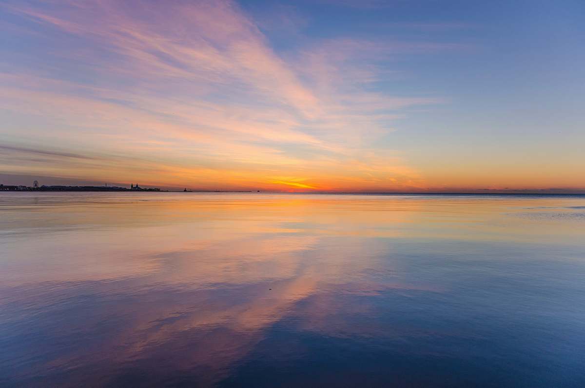 sunrise body of water under cloudy sky sky