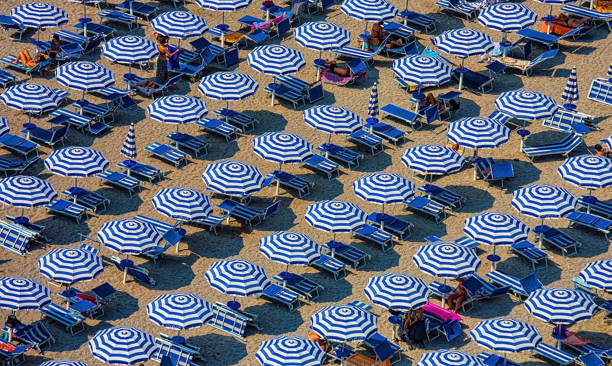summer aerial photography of blue-and-white patio umbrellas sand
