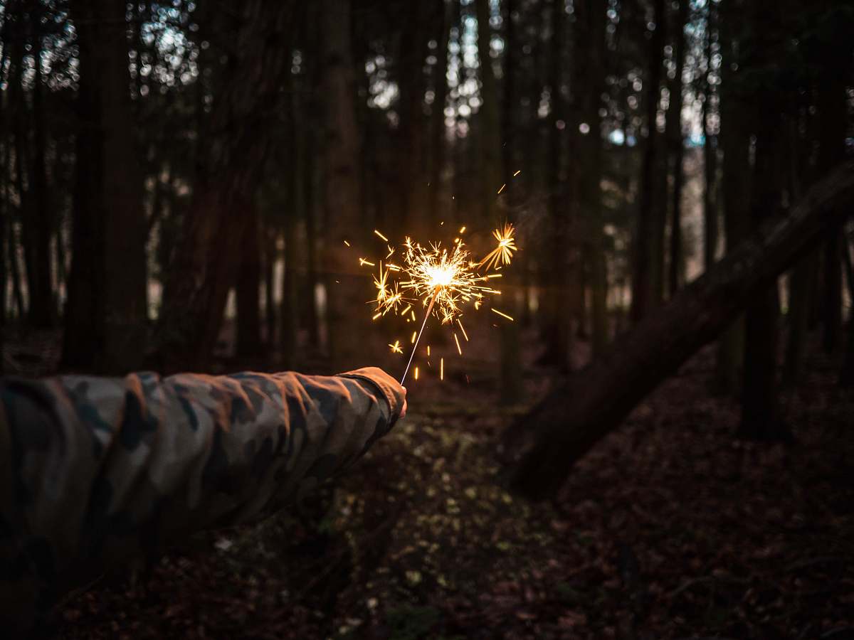 forest person holding sparkler at the middle of forest outdoors