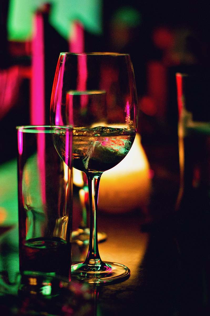 drink half filled wine glass beside half empty clear pint glass alcohol