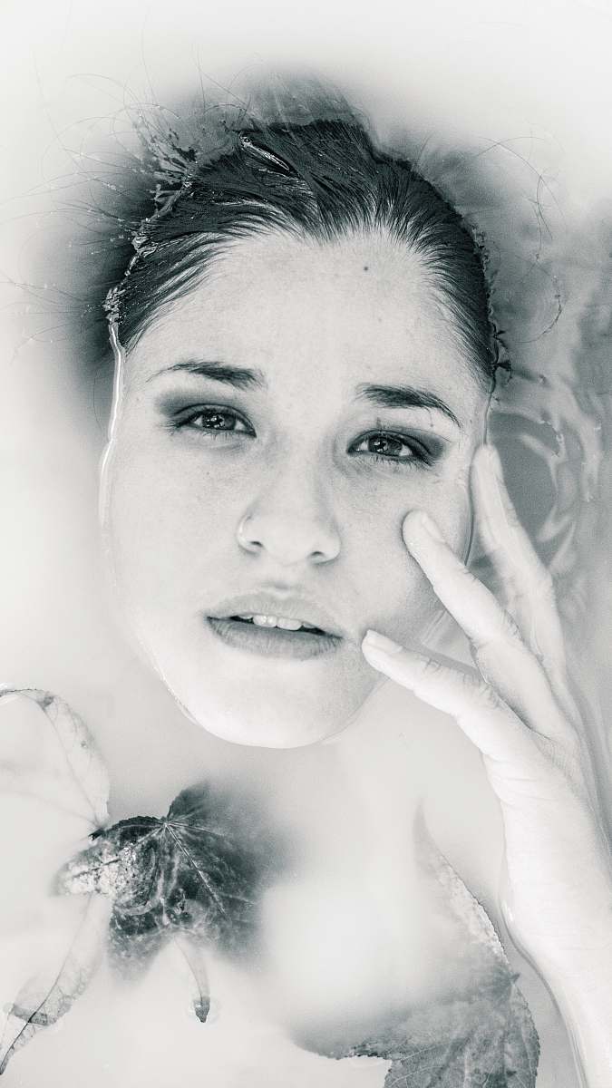 person grayscale photo of woman lying on body of water face