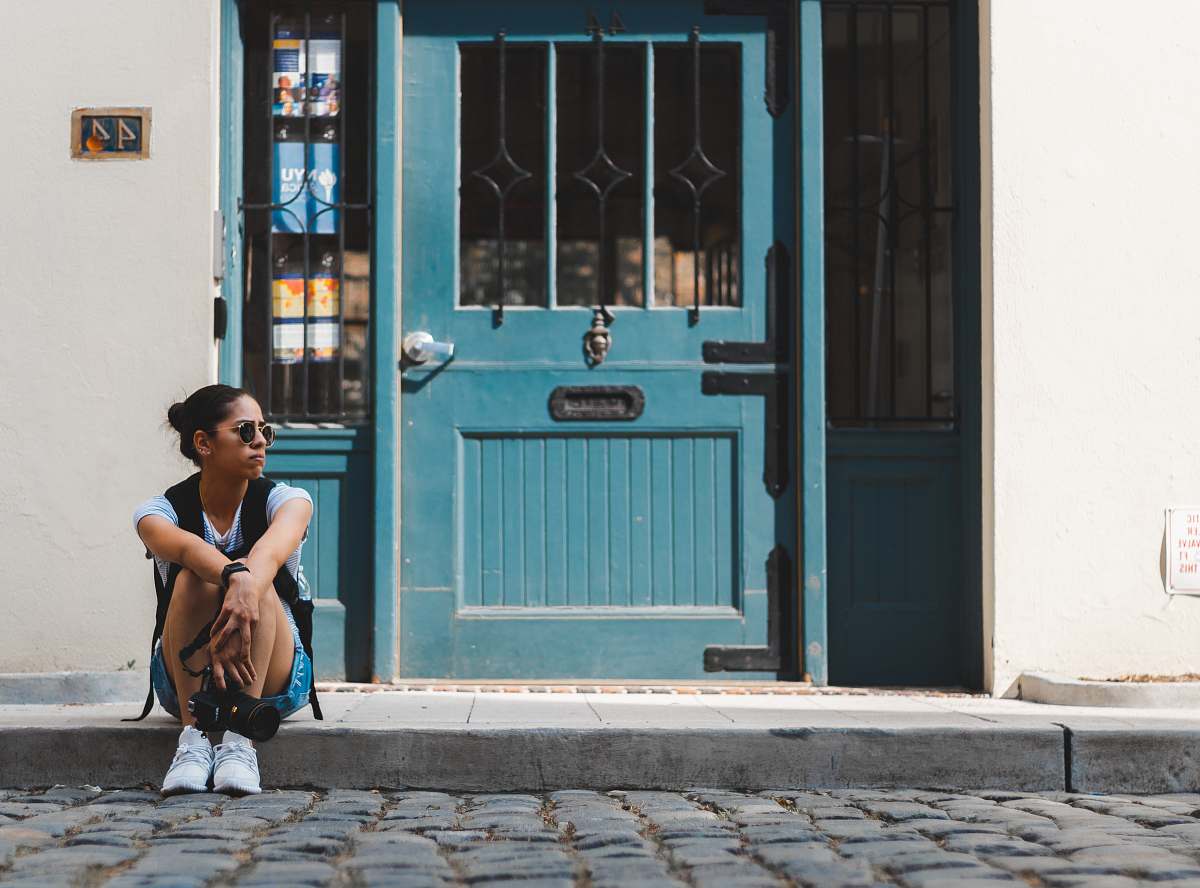 person woman sitting near blue door people