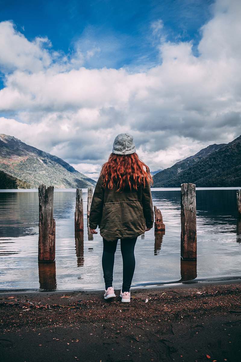 apparel woman standing facing body of water clothing