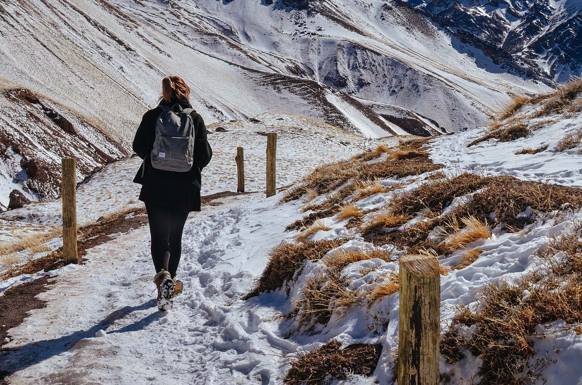 person woman walking near mountain covered by snow during daytime people